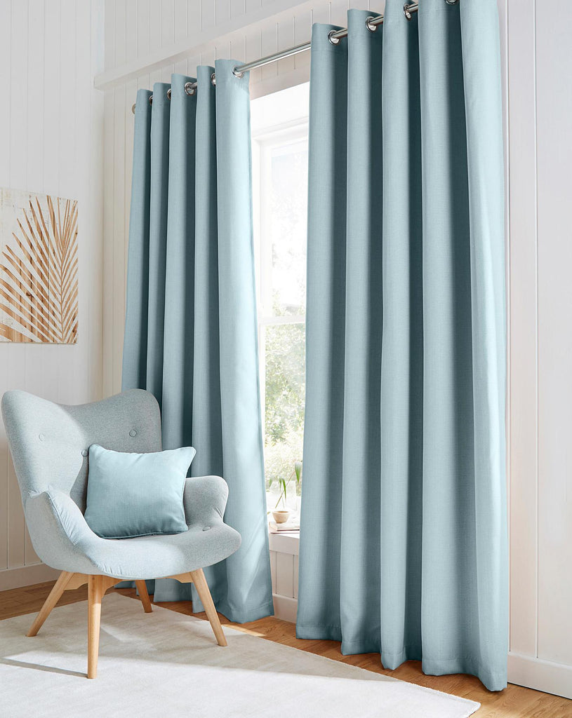 light blue curtains and a grey chair with a blue cushion